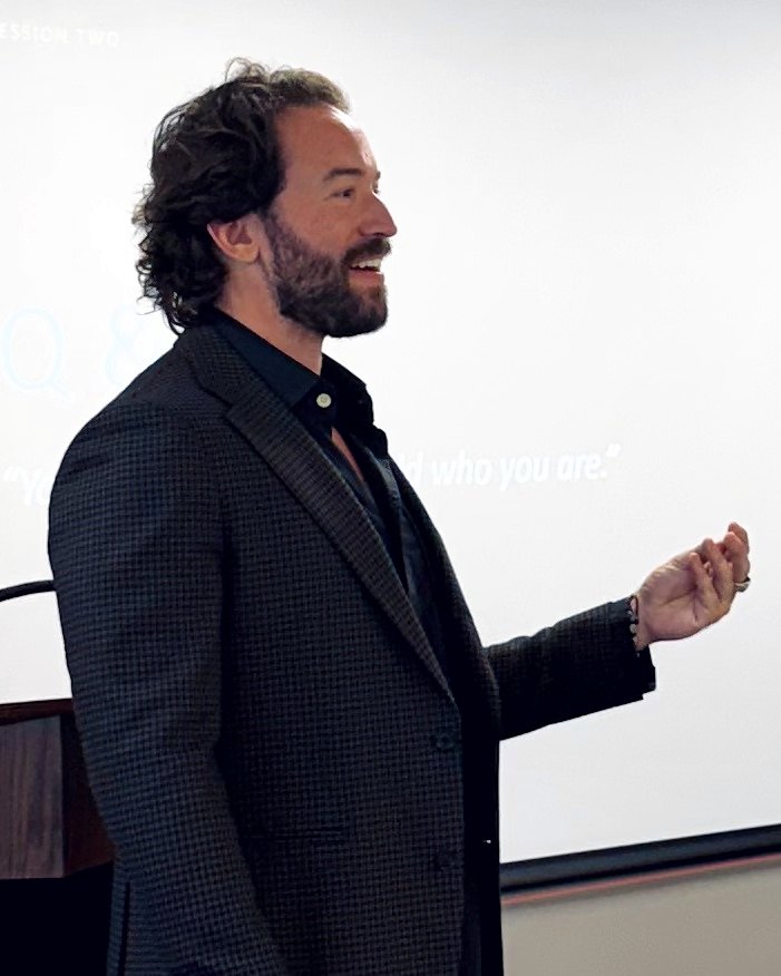 Michael Hewitt speaking at a workshop, with “who you are” on the slide behind him