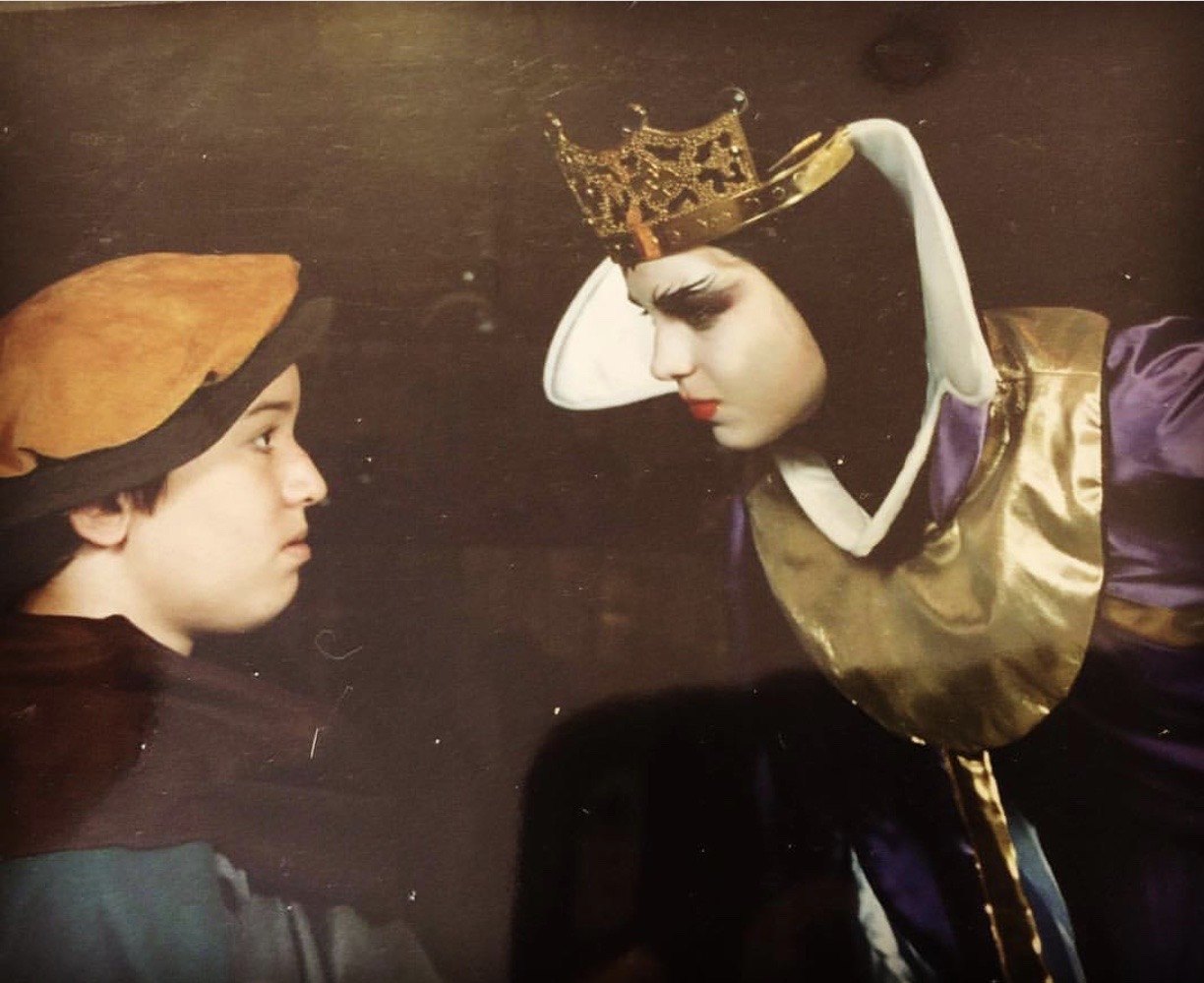 Michael in a cap, face to face with Melissa in a crown and royal costume