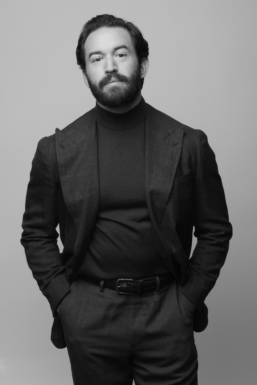 Black-and-white studio portrait of Michael Hewitt in a dark suit and turtleneck